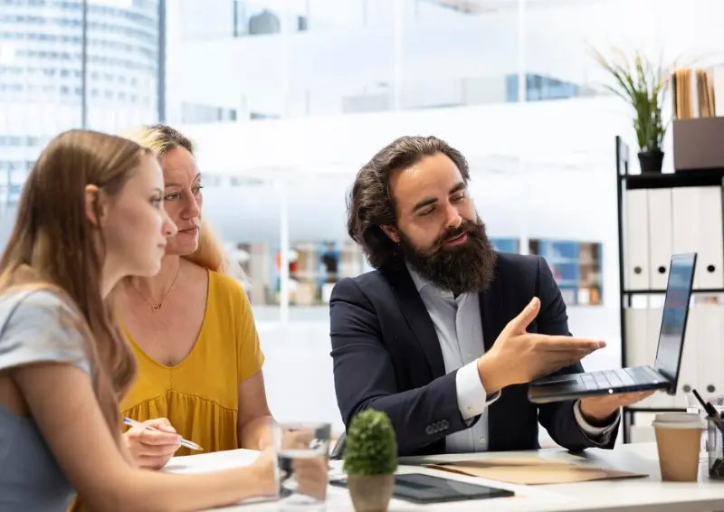 Consultant presenting data on laptop to clients business directory